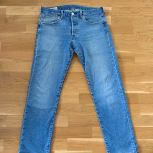 Levi's 501 jeans - Klassiska ljusblå Levi's 501 jeans med raka ben och fem fickor. Byxorna har knappgylf och den ikoniska läderpatchen bak i midjan. Perfekta för dig som gillar tidlös denimstil. Upplagda till ungefär L28.