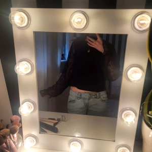 Svart spetsblus från NA-KD - Säljer en svart, croppad blus från NA-KD med långa ärmar i spets. Blusen har blommigt spetsmönster och rund halsringning. Perfekt för dig som vill ha en trendig och elegant topp med transparenta ärmar.