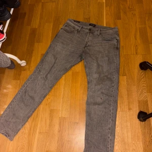Jack & Jones jeans - Hej, Säljer ett par Jack & Jones jeans i modellen Tapered Mike, Stl 32/32. Säljer då jag gått ner några kg så de sitter inte längre. Köptes September 2024 för 599kr och har använts ett fåtal gånger sedan dess då jag föredrar blåa jeans. Ett par gråa jeans är ett måste i jeans-kollektionen så slå till för en liten peng! Bara att höra av sig vid frågor.