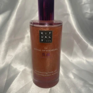 Shimmering body oil från Rituals The Ritual of Yozakura - Shimmering body oil från Rituals The Ritual of Yozakura med svart ris och japansk körsbär. Oljan har en skimrande finish och kommer i en genomskinlig flaska med lila lock. Perfekt för att ge huden en glansig look. Oanvänd 