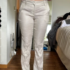 Beiga linnebyxor från Nelly - Snygga beiga linnebyxor från Nelly med Low waist. De är lite skrynkliga nertill men det gör lätt att fixa, så de är egentligen bootcut! Byxorna har hällor för bälte och diskreta fickor. Perfekta för en stilren och avslappnad look😍 aldrig använt så i topp skick 