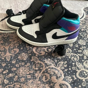 Nike Air Jordans i svart, vitt och lila - Säljer ett par Nike Air Jordans  Perfekta för dig som gillar streetwear och vill sticka ut med färg.