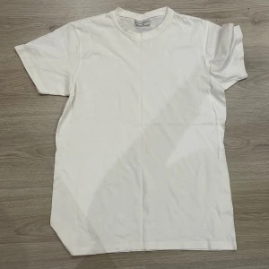 Vit t-shirt från Buxbom - Klassisk vit t-shirt från Buxbom med rund halsringning och korta ärmar. Storlek L