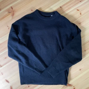 Mörkblå stickad tröja med rund hals - En enkel och stilren mörkblå stickad tröja med rund halsringning och långa ärmar. Tröjan har ribbade muddar vid ärmslut.