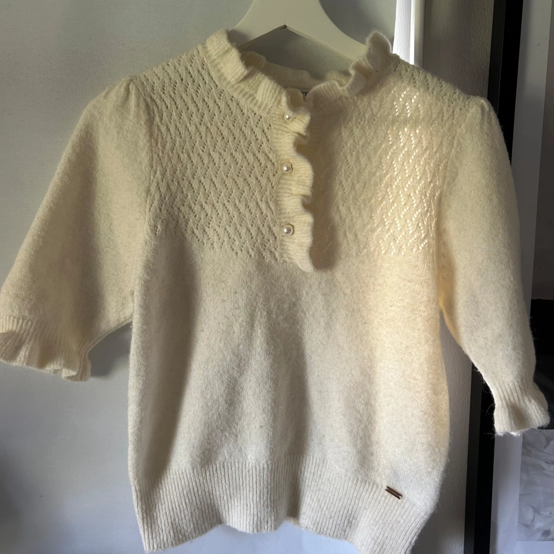 Vit stickad tröja med volang och pärlknappar