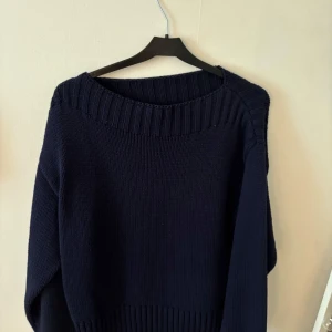 Mörkblå stickad tröja från Gina Tricot - Säljer en mörkblå stickad tröja från Gina Tricot. Tröjan har en bred ribbad kant vid halsen och är långärmad med en avslappnad passform. Använt max 2 gånger😊