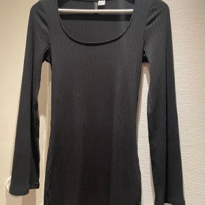 Svart ribbad långärmad klänning Gina Tricot - En svart, ribbad och figurnära klänning från Gina Tricot med lång ärm och rundad urringning. Enkel och stilren design.