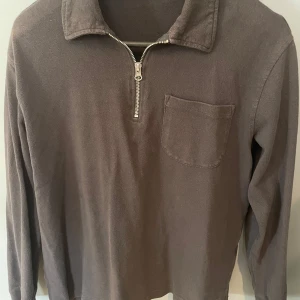 Grå half zip tröja från Weekday - Säljer en oanvänd grå långärmad tröja från Weekday med krage och half zip-dragkedja framtill. Tröjan har en bröstficka och är gjord i mjuk bomull. Perfekt för dig som gillar en clean och avslappnad stil. Nypris 900kr