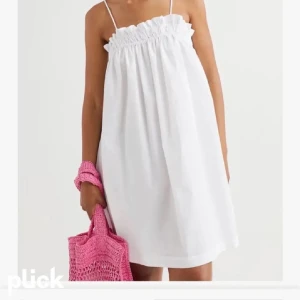 Vit kort sommarklänning med smala band - Superfin vit klänning med smala axelband och rynkad volang upptill. Luftig och flowy modell som är perfekt för varma dagar. Enkel och stilren design som passar till sneakers eller sandaler.