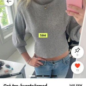 Grå ribbad stickad tröja - Snygg grå stickad tröja med ribbat mönster och trekvartsärmar. Tröjan är croppad och har en högre hals, perfekt för lager-på-lager-stil. Enkel att matcha med både jeans och kjol.