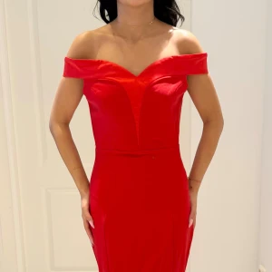 Röd offshoulder långklänning - Snygg röd långklänning med offshoulder och figurnära passform. Klänningen har en markerad v-ringning och dragkedja i ryggen. Perfekt för bal eller festliga tillfällen. Materialet känns slätt och följsamt.
