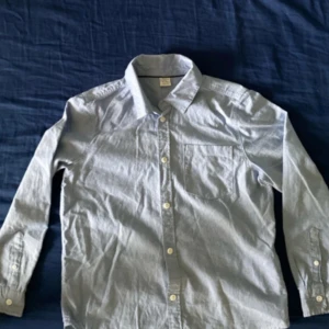 Ljusblå bomullsskjorta med knappar - ljusblå skjorta i bomull med lång ärm, vita knappar hela vägen framtill.