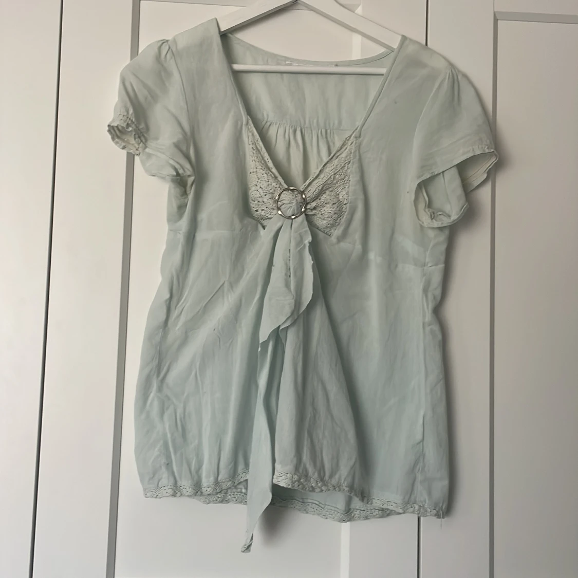 Ljusblå blus med spets och ringdetalj