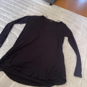 Svart långärmad topp Gina Tricot XS - En svart långärmad topp från Gina Tricot i storlek XS. Tunt och mjukt material med rund hals och smala snören vid axlarna. Perfekt att styla med jeans eller kjol för en clean look.