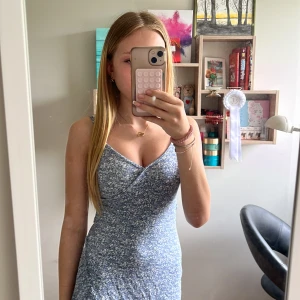 Blommig blå kortklänning  - Supersöt blå kortklänning från Gina Tricot med vita blommor, omlott-v-ringning och volangkant nertill. Klänningen har smala axelband och sitter snyggt figurnära. Jättebra skick, aldrig använd. Strl 146/152 men är stretchig Perfekt för sommaren 💞