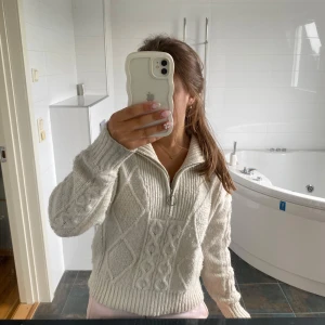Vit stickad tröja med half zip - Mysig vit stickad tröja med grovt kabelstickat mönster och ribbade muddar. Tröjan har en hög krage och en snygg half zip-dragkedja framtill. Perfekt för lager på lager och chill dagar. Säljer pga ingen användning!🌸💗
