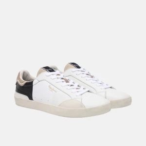 Pepe Jeans Skor | HELT NYA - Snygga sneakers från Pepe Jeans i vitt och svart med beige och bruna detaljer. Skorna har klassisk låg profil, vit sula och snörning. Ovandelen är i skinn och mocka, med diskret logga i guld på sidan och '1973' präglat på hälen. Perfekta för en clean och stilren look. Aldrig Använda