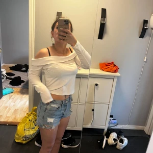 Vit offshoulder långärmad topp - Säljer en vit, ribbad offshoulder topp med lång ärm. Tröjan är croppad och har en snygg, figurnära passform som framhäver axlarna. Perfekt för dig som gillar en stilren och trendig look till sommaren. Storlek L men sitter som en M