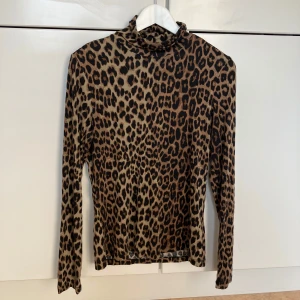 Leopardmönstrad polotröja H&M  - Snygg leopardmönstrad polotröja från H&M i stretchigt material.  Färgerna går i beige, brunt och svart vilket gör den lätt att matcha med jeans eller kjol. Perfekt för dig som vill sticka ut lite extra.