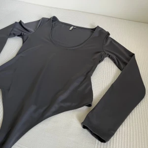 Svart långärmad bodysuit från Nelly - En stringbody från Nelly. Det verkar inte längre som att denna vara går att köpa via Nelly hemsida. Bodyn har ett glansigt material vilket ger en lyxig känsla. Den har en djup urringning framtill och formar kroppen väldigt bra. 