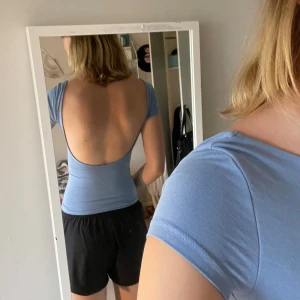 Ljusblå topp med öppen rygg Gina Tricot - Supersnygg ljusblå topp från Gina med tight passform och korta ärmar. Toppen har en djup, öppen rygg som ger en cool och unik look. Mjuk och stretchig i bomullsmix, perfekt till jeans eller kjol när du vill sticka ut lite extra.