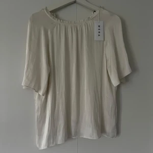 Ljusbeige blus från Wera i silke - GARDEROBSRENSNING! Superfin ljusbeige blus från Wera i silkesmaterial. Blusen har lös passform, korta ärmar och en lätt rynkad halsringning som ger en avslappnad men stilren look. Perfekt att styla med jeans eller kjol för en trendig vibe. Aldrig använt! Köpt för 399kr