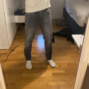 Grå jeans från Jack & Jones, 33/32 - Säljer ett par grå jeans från Jack & Jones i storlek 33/32. Jeansen har klassisk femficksdesign, rak passform och är tillverkade i mjukt denimtyg. Perfekta för dig som gillar en stilren och enkel look.