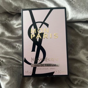 YSL Mon Paris Eau de Parfum 30ml (Oanvänd) - YSL Mon Paris Eau de Parfum i 30ml flaska. Parfymen kommer i en lyxig, transparent glasflaska med ljusrosa doftvätska och en elegant svart rosett med gulddetalj vid halsen. Snygg och modern design, perfekt för dig som gillar exklusiva dofter. Den är helt oanvänd och köptes för 950kr