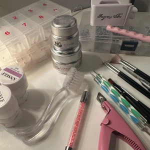 Nagelsaker  - Säljer ett kit med färgade nagelgeler från Anself i flera nyanser som orange, lila, grön och rosa samt genomskinligt builder gel från NG. Inkluderar olika penslar, dotting tools och nagelverktyg. Perfekt för dig som gillar att fixa naglarna hemma och vill ha många färger att välja på. (Kommer att rengöra allting inna jag sickar💕)