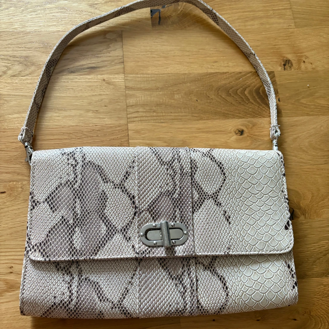 Beige axelväska med ormmönster