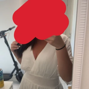 Vit omlottklänning med volang - Supersöt vit kortklänning med omlott och v-ringning. Klänningen har markerad midja, volangig kjol och korta ärmar. Perfekt för sommarens alla tillfällen och ger en fräsch och luftig känsla. Endast använd en gång. Säljer den eftersom den inte riktigt är min stil.