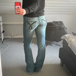 Blå bootcut jeans med svarta detaljer  - Säljer ett par långa blå bootcut jeans i st S/M då de inte längre kommer till användning. Midjemåttet är ca 40cm och innerbenslängd ca 88cm, de passar perfekt på mig som är 178.