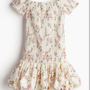 Hm blommig klänning - Supersöt kortklänning i ljus färg med blommigt mönster och volang nertill. Inte använd och därav mycket bra skick