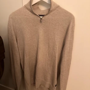 Grå half zip tröja Jack & Jones - Grå långärmad tröja från Jack & Jones med half zip-dragkedja i halsen. Tröjan är i mjuk bomullsmix och har en stilren, enkel design med ribbade muddar och krage. Perfekt för lager-på-lager och chill stil.