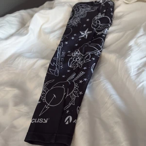 Svart Aimlabs ärm med vita motiv S - Säljer en svart ärm från Aimlabs i storlek S, tillverkad i stretchig polyester och spandex. Ärmen har coola vita motiv med stjärnor, hjärtan och text. Perfekt för gaming eller träning när du vill ha stil och komfort. (Använd endast en gång ny pris 150kr)