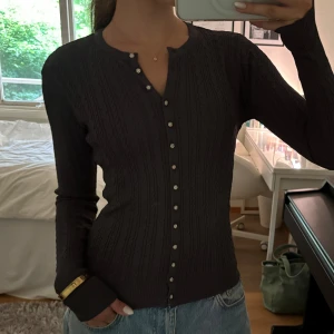 Mörkgrå stickad kofta - Supersnygg mörkgrå kofta med kabelstickat mönster och glittriga blomformade knappar