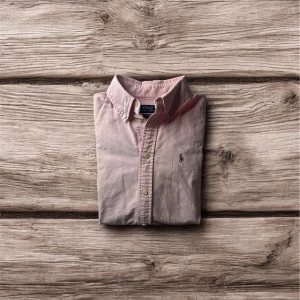 Rosa skjorta från Polo Ralph Lauren XS - 🔹 Detaljer: ✔ Färg: Ljusrosa ✔ Storlek: XS (Dam) ✔ Material: 100% bomull ✔ Skick: Mycket bra – fräsch och välbevarad ✔ Logga: Klassisk broderad Polo-logga  En tidlös skjorta du kan bära öppen över ett linne, instoppad i jeans eller uppklädd med kavaj – du väljer.  📦 Kan skickas snabbt eller mötas upp 📩 Skriv om du vill ha fler bilder eller mått. Den här förtjänar att bli buren, inte ligga i garderoben!