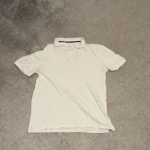 Vit pikétröja med krage - Klassisk vit pikétröja från Eton med korta ärmar och krage. Tröjan har knappar framtill och är tillverkad i mjuk bomull, perfekt för en clean och stilren look.