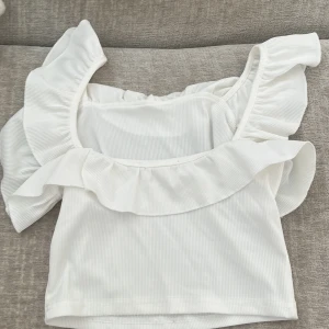Vit croppad topp med volang - Säljer denna vita topp men lapp saknas men skulle säga att det är storlek Xs💕