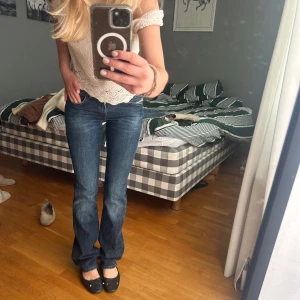 Mörkblå bootcut jeans låg midja - Säljer ett par mörkblå jeans med snygg bootcut och låg midja. Jeansen har klassiska fickor fram och bak, diskreta slitningar och är tillverkade i stretchigt denim för en bekväm passform. Perfekta till sneakers eller ballerinas.