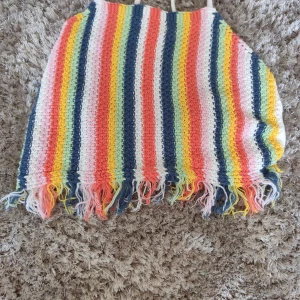 Randig virkad linnetopp från Zara - Färgglad virkad linnetopp från Zara med smala axelband och fransar längst ner. Toppen har ränder i vitt, blått, gult, orange och rosa. Perfekt för sommarens alla äventyr och ger en riktigt glad vibe.