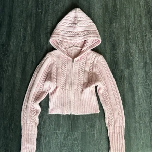 Stickade ljusrosa mjukisbyxor och kofta - Supermysiga stickade mjukisbyxor i ljusrosa med bred ribbad midja och kabelstickat mönster. Byxorna har en loose passform och är perfekta för chill dagar hemma. Materialet är mjukt och stretchigt, vilket gör dem extra bekväma.