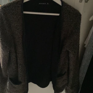 Mysig teddyjacka från Rut&Circle - Säljer en brun teddyjacka från Rut&Circle med öppen front och två fickor. Jackan har en fluffig och mjuk känsla, perfekt för kyliga dagar. Enkel och stilren design som passar till många outfits.