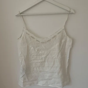 Vit linnetopp - Säljer en stilren vit linnetopp med smala axelband och en enkel design. Perfekt för varma dagar eller som ett basplagg i garderoben. Den är i Xs och är typ aldrig andvända, tror den är från Mango