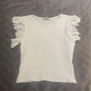 Vit stickad topp med spetsvolang - Superfin vit stickad topp från Zara med korta ärmar och snygga spetsvolanger. Passar mellan storlekarna xs och S 