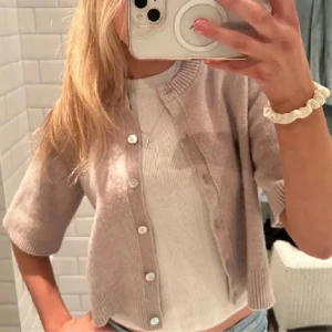Other stories kofta med kort ärm - Superfin beige kofta från other stories  bra skicka och säljs inte längre. Perfekt att slänga över en topp för en chill och stilren look. Första bilden är lånad från tidigare säljare