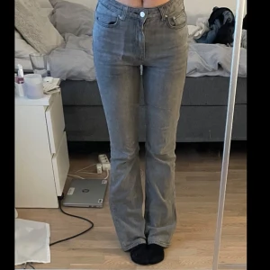 Grå bootcut jeans från - Snygga grå jeans i bootcut-modell. Jeansen är midwaist, klassisk femficksdesign och är tillverkade i ett mjukt denimtyg. Perfekta för dig som gillar en tidlös look med lite utsvängda ben.