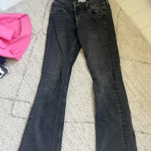 Gråa bootcut jeans Gina Tricot - Snygga gråa bootcut jeans från Gina Tricot. Jeansen har klassiska fem fickor, knappar med logga och bakfickor med lock. Perfekta för dig som gillar en lite vidare passform nertill och vill ha en cool vardagsstil. Knappt använda och är i storlek 158 men passar mig som bär Xs/S. 