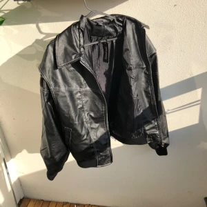 Svart skinnjacka  - Snygg svart skinnjacka från Boohoo med vita kontrastsömmar och dragkedja framtill. Jackan har en klassisk krage, ribbade muddar och en lite oversized passform. Jag råkade köpa två likadana så därför är det två likadana annonser i min profil.