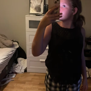 Svart ärmlös blus från H&M - Svart ärmlös blus från H&M med snyggt virkad detalj upptill och rundad halsringning med liten kant. Perfekt att styla med jeans eller kjol för en chill look. Luftig och skön modell som passar året runt.